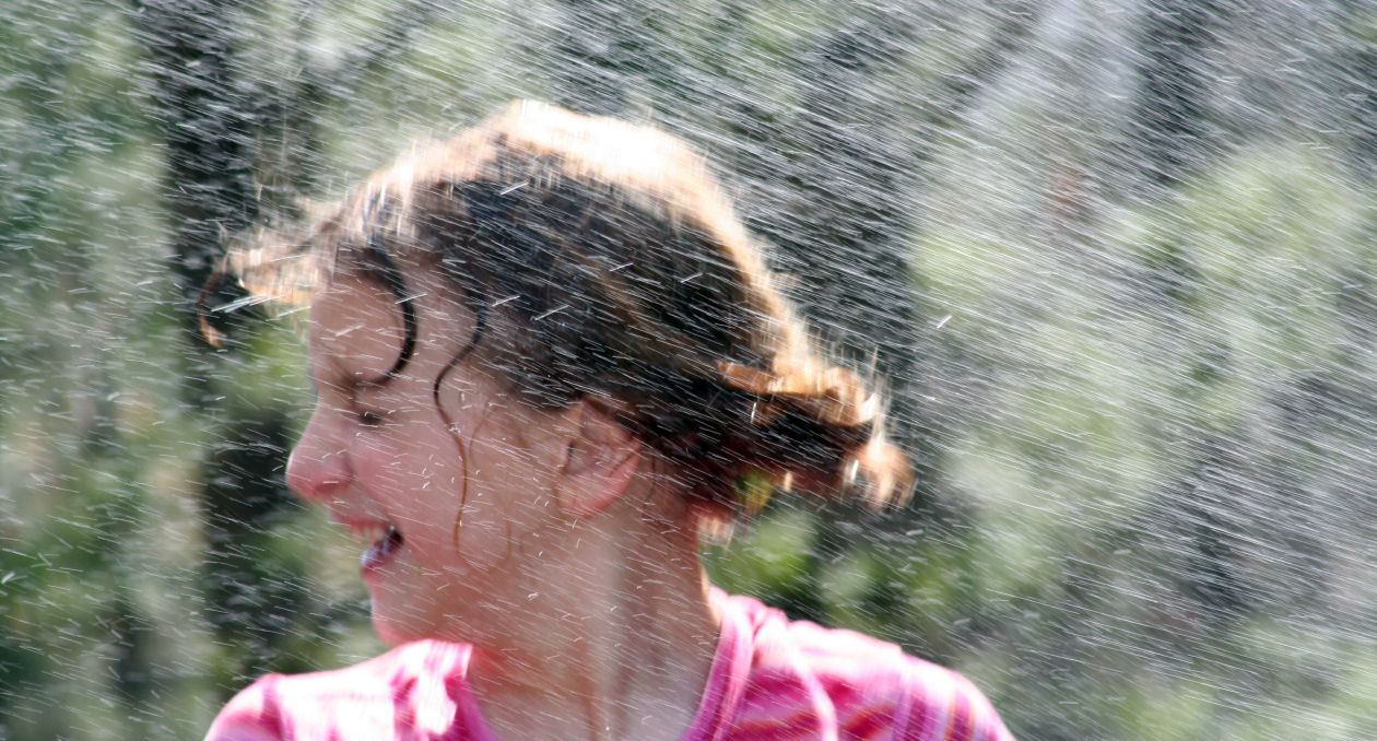 das Bild zeigt eine glückliche, lachende, regennasse Frau von der Seite. Sie findet es gut, dass Entrümpelungen kostenlos angeboten werden.